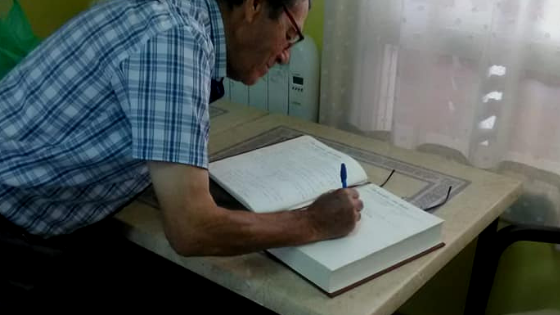 Persona mayor escribiendo en el libro de afectos de la exposición Mirando al Futuro